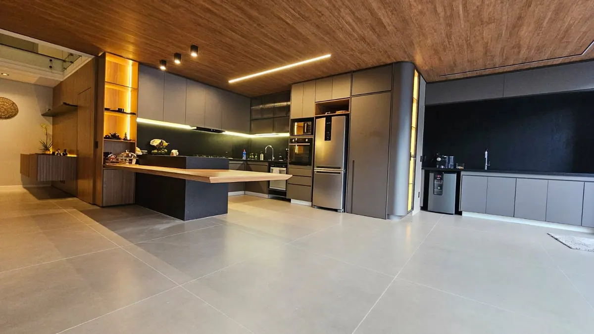 Cozinha integrada com armários cinza, ilha com tampo de madeira e LED