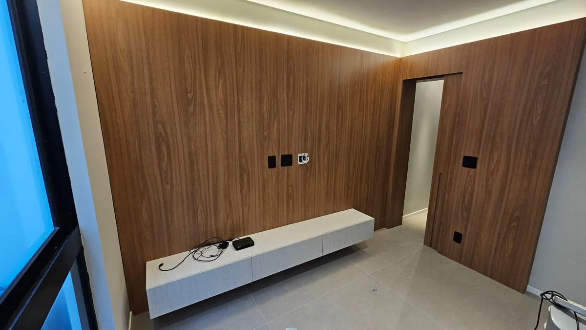 Painel em madeira escura com porta oculta: Sala