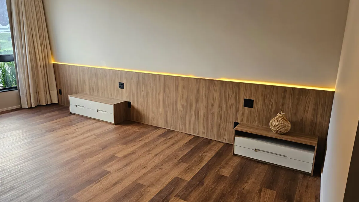 Painel baixo amadeirado com LED e criados-mudos brancos